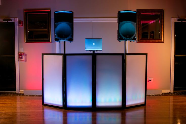 DJ booth with illuminated facade and tall speaker stands